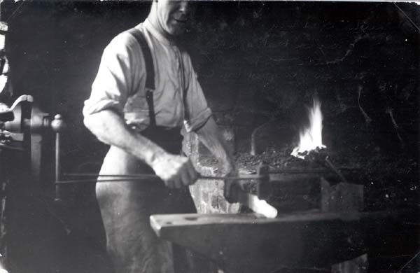 Benny Burton beating out a  new horsheshoe at the  Forge